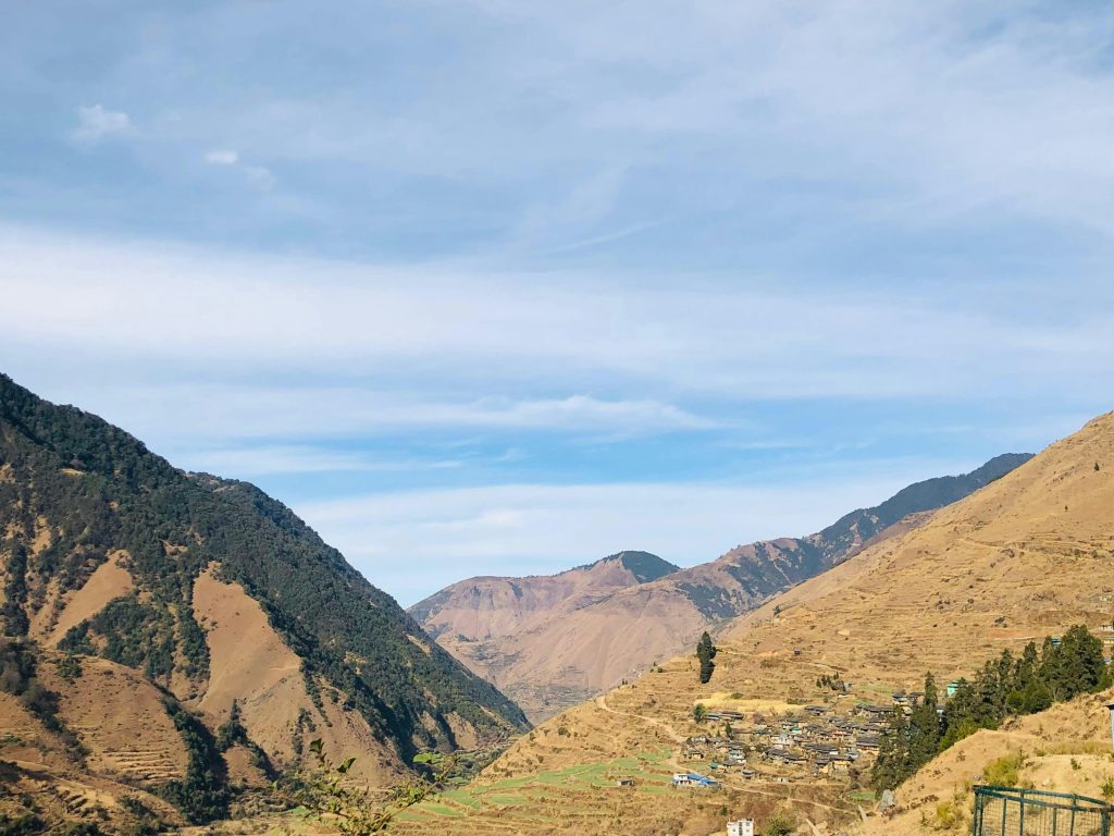 This wide shot portrays a Himalayan valley with farms and a village by the river. It emphasizes the integration of human settlements with agricultural land and the importance of valley farming for food security.